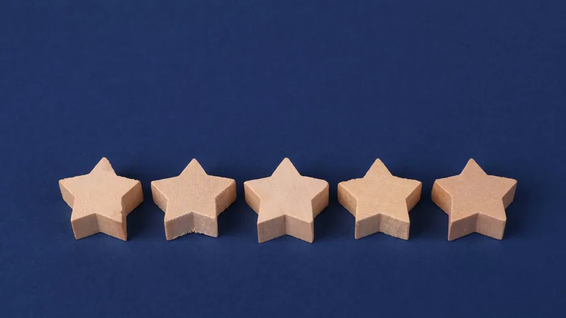 Fünf Sterne aus Holz in einer Reihe auf dunkelblauem Hintergrund – Symbolbild für Google-Bewertungen