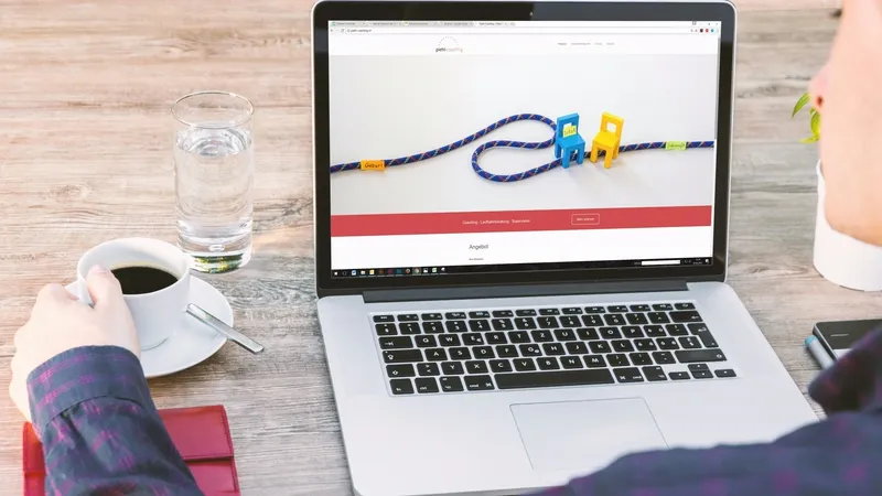 MacBook auf einem aufgeräumten Schreibtisch neben Kaffeetasse und Wasserglas – Symbolbild für fokussiertes Arbeiten an einer klaren, einseitigen Website